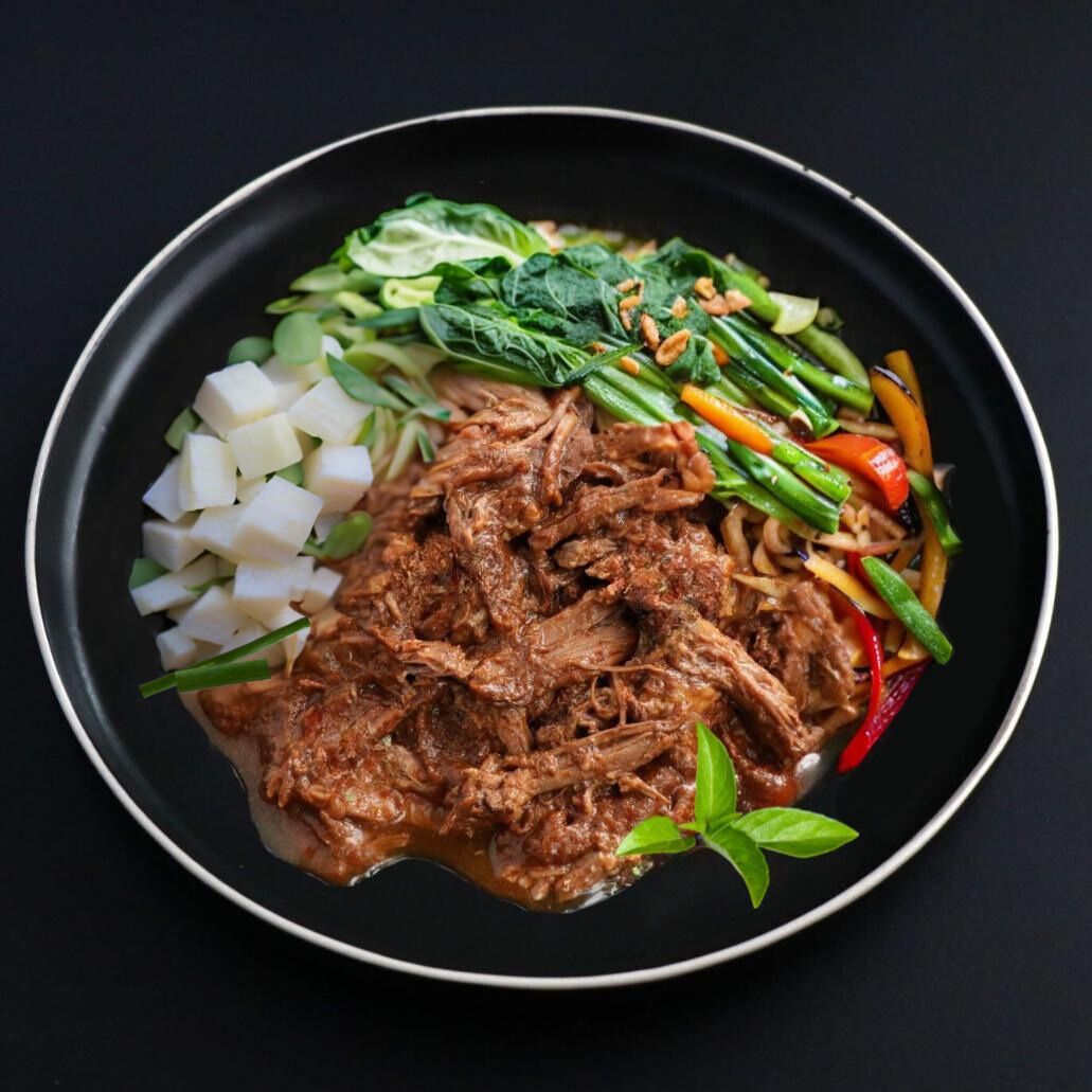 Paleo dish of tender pulled beef covered with rich red Thai curry sauce and complemented with potato bites and variety of oriental veggies and Thai basil leaf.