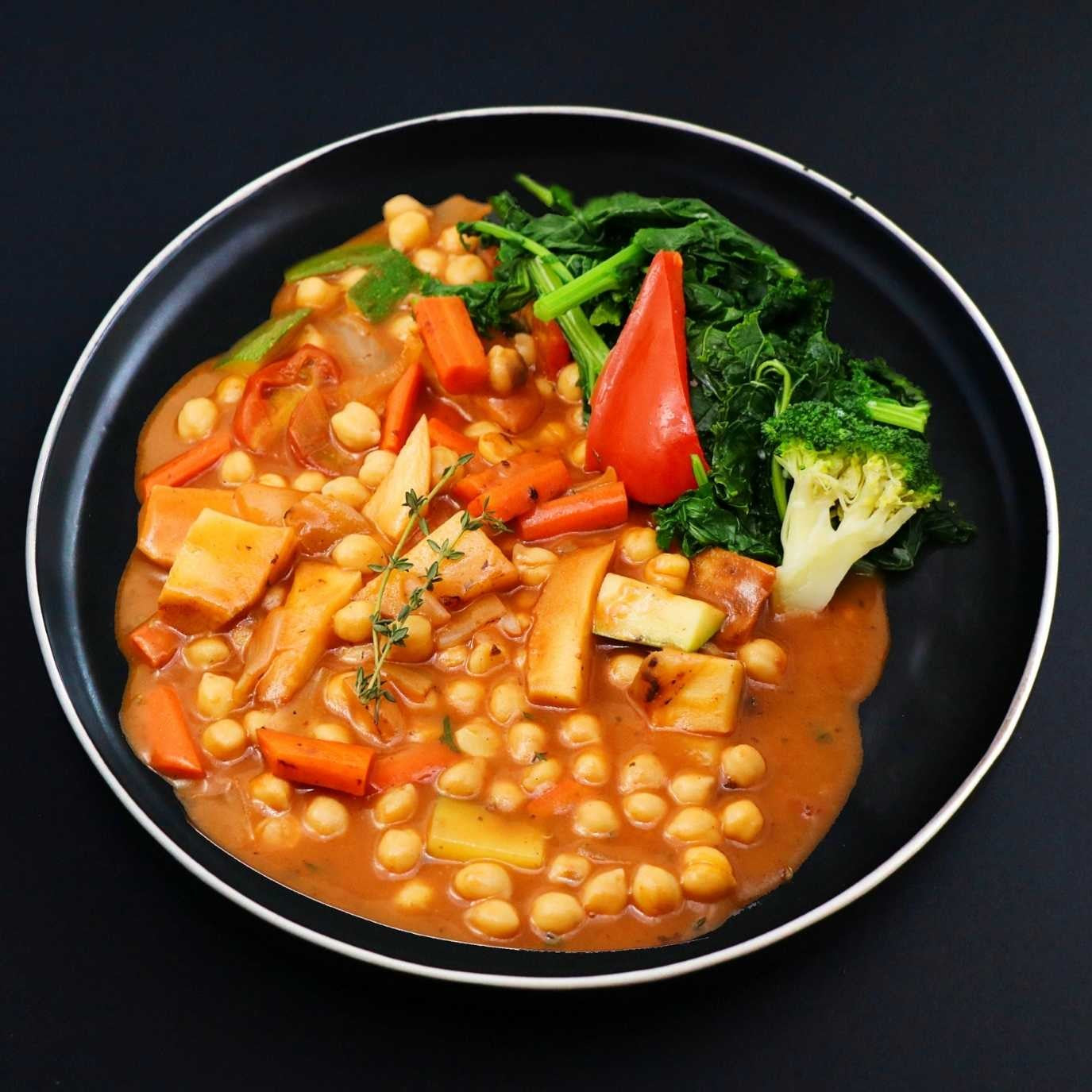 Aromatic and rich roasted vegetable chickpea stew come with side of seasonal vegetables and herbs.