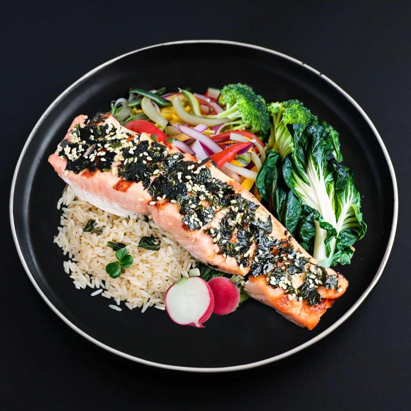 A plate with a Gourmet Nori Sesame Crusted Salmon, Brown Rice, and Broccoli.