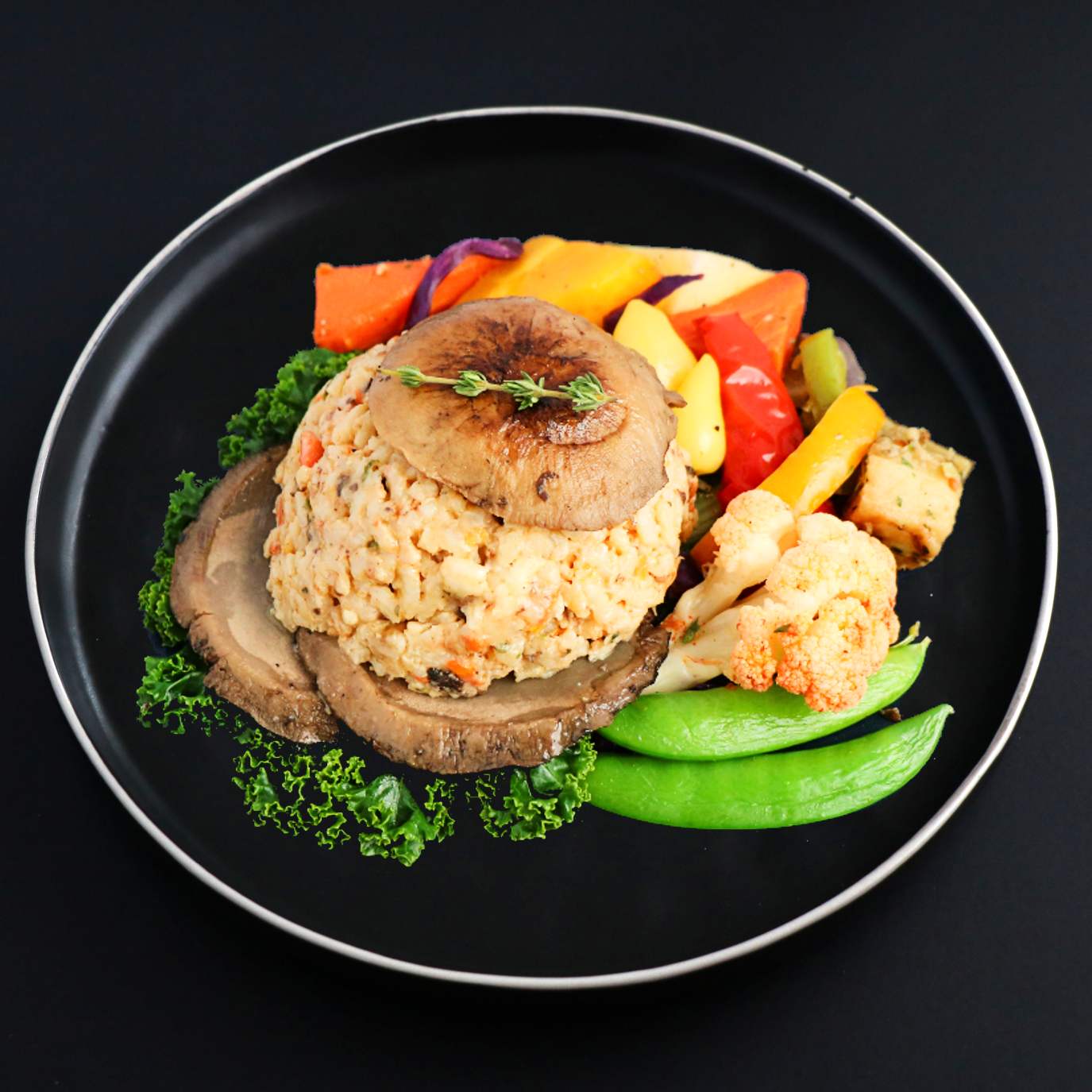 A plate with a stuffed portobello mushroom filled with a creamy blend and surrounded by sautéed vegetables such as peppers and peas, garnished with parsley.