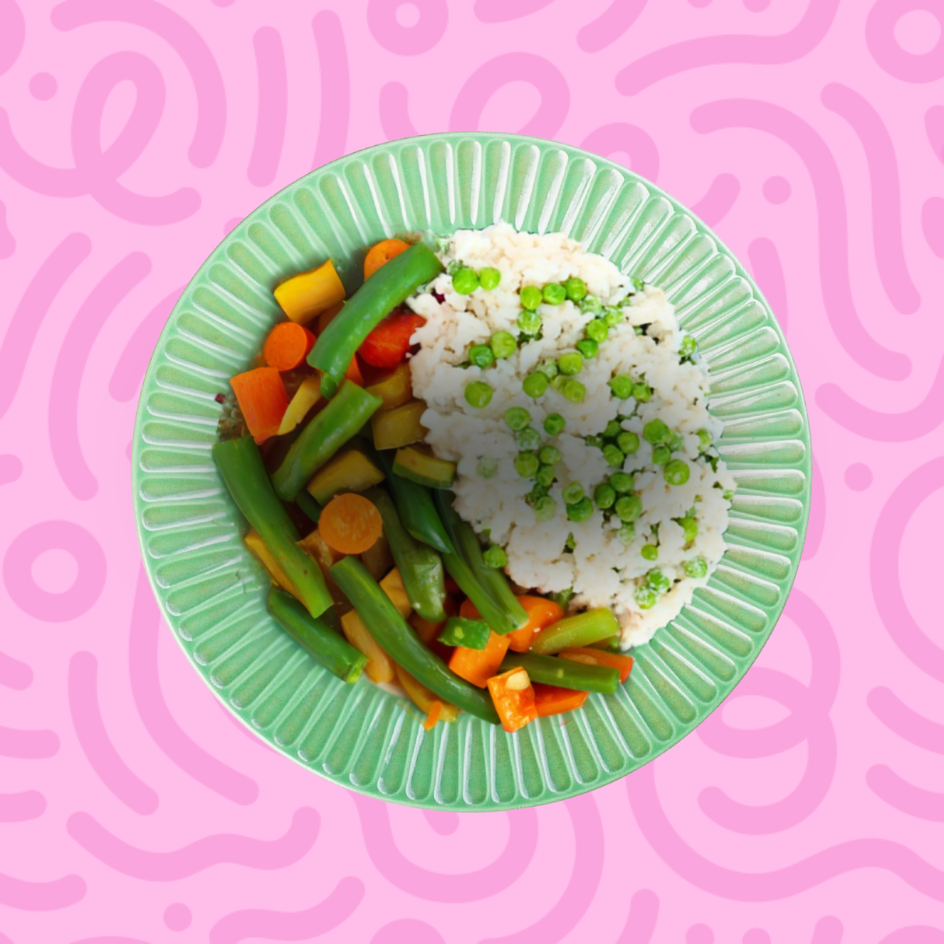 Vegan cauliflower rice bowl with green peas, steamed green beans, carrots, and squash on a pink patterned background.