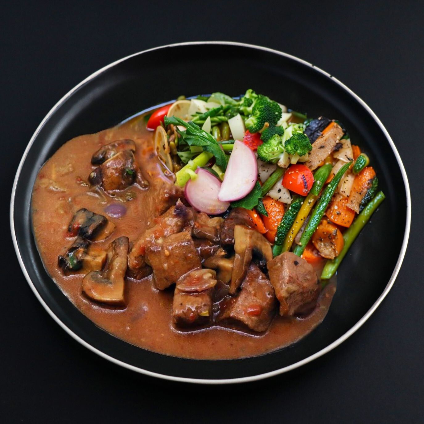 A plate of balanced Beef Bourguignon with tender chunks of beef in a rich velvety sauce, served with steamed vegetables.