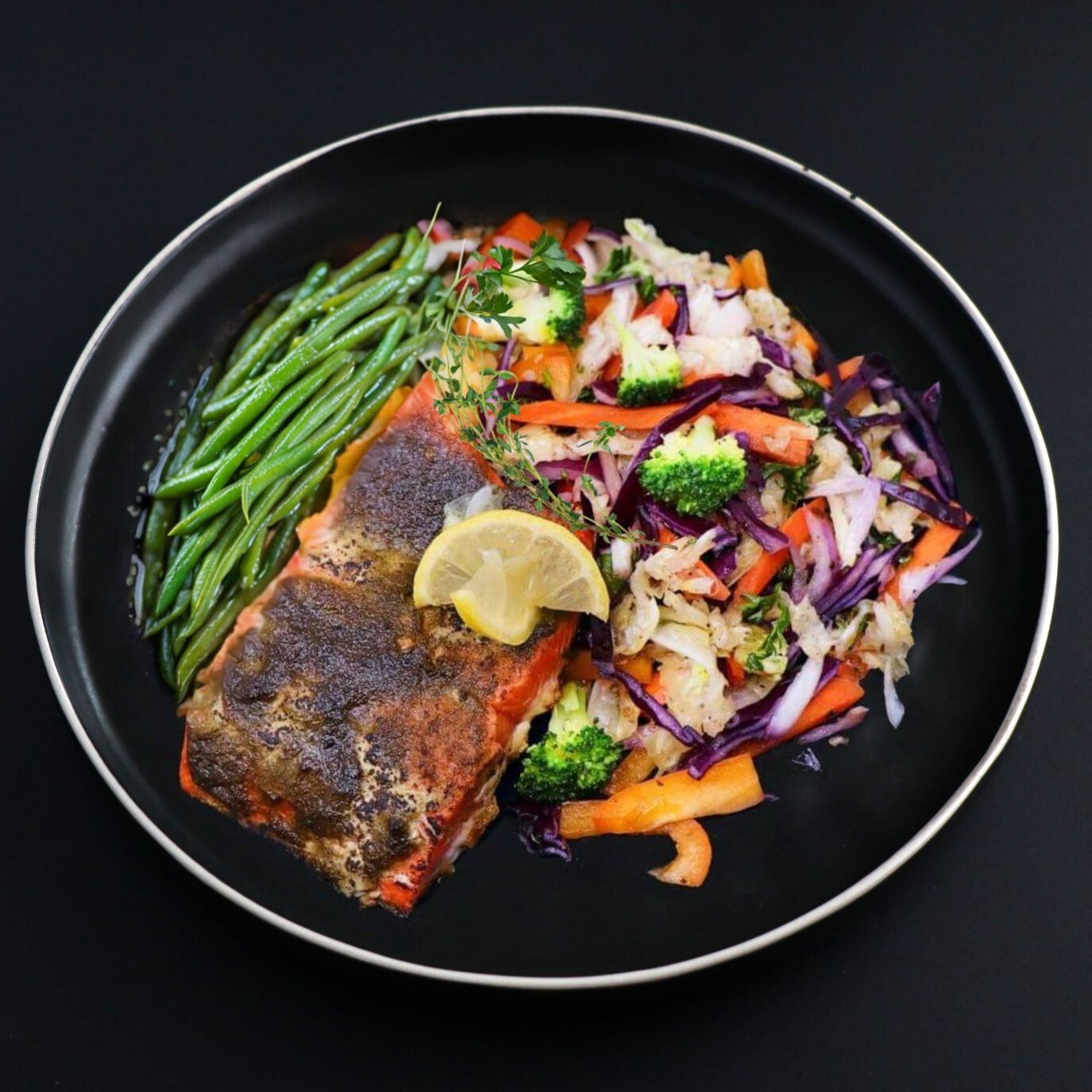 Slice of tender Jerk Salmon fillet served with a side of green beans and other veggies making it a perfect Jamaican flavour escape.