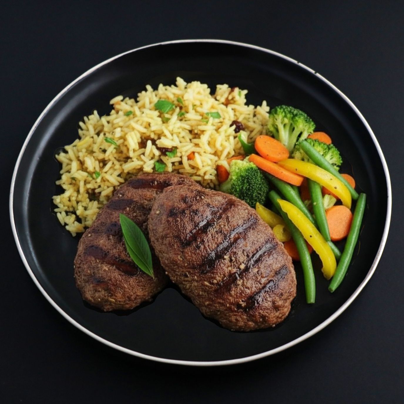 Plated dish with grilled beef cutlets, side rice pilaf and assorted vegetables such as green beans, broccoli and carrots.