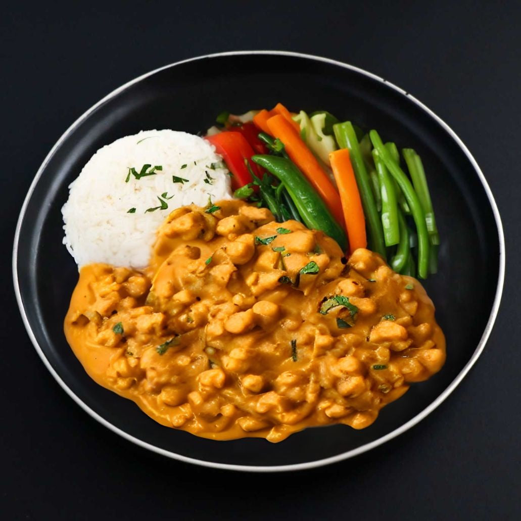 A plate of Butter Cauliflower Chickpea Curry served with Basmati rice and garnished with fresh parsley, cilantro, and a slice of tomato.