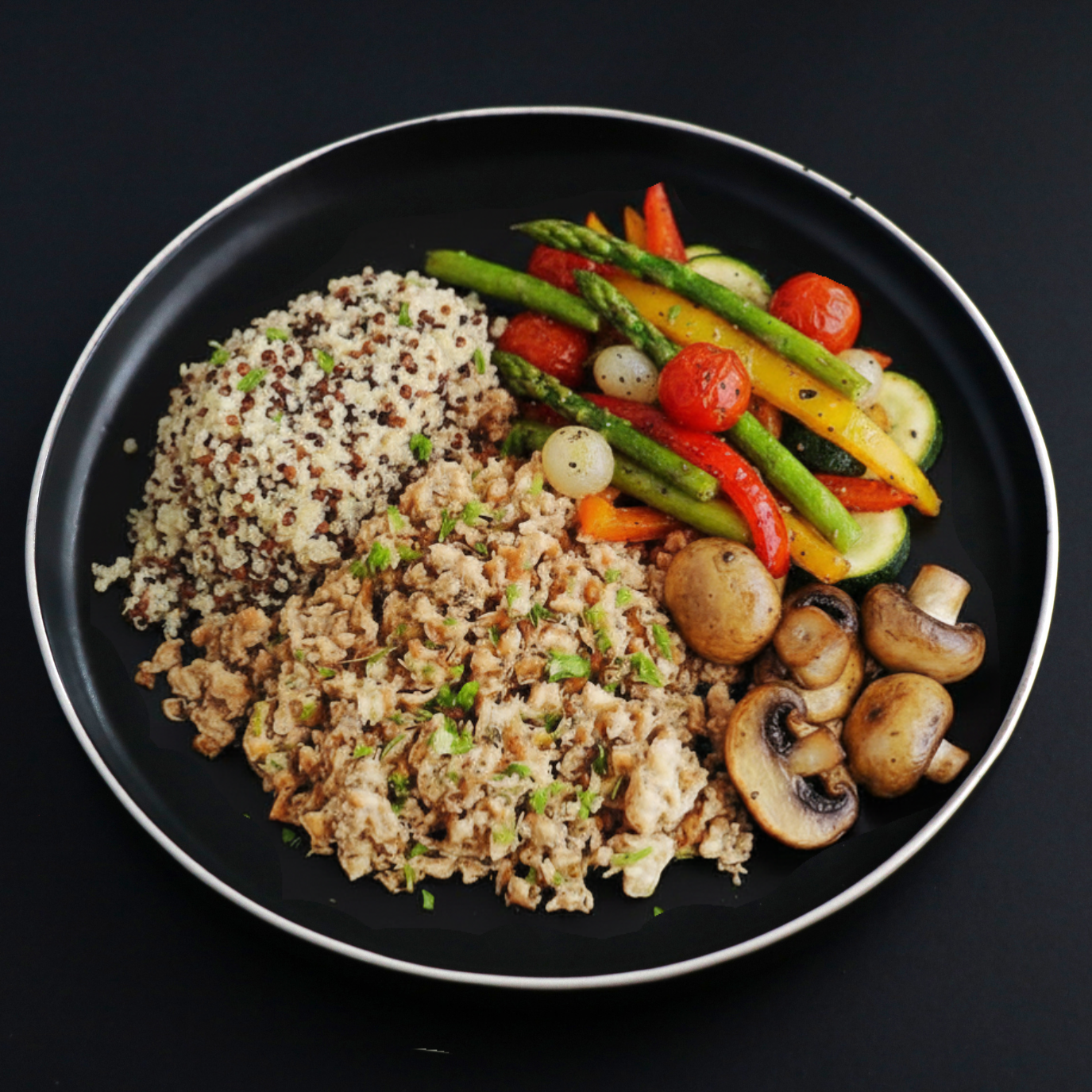Plated dish of lean ground turkey sided with quinoa and assorted vegetables such as asparagus, tomatoes and zucchini