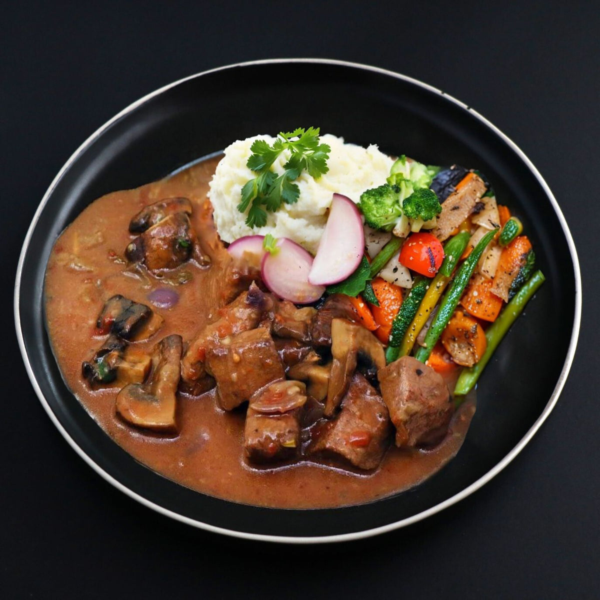 A plate of paleo Beef Bourguignon with creamy mashed potato and mixed vegetables served on the side.