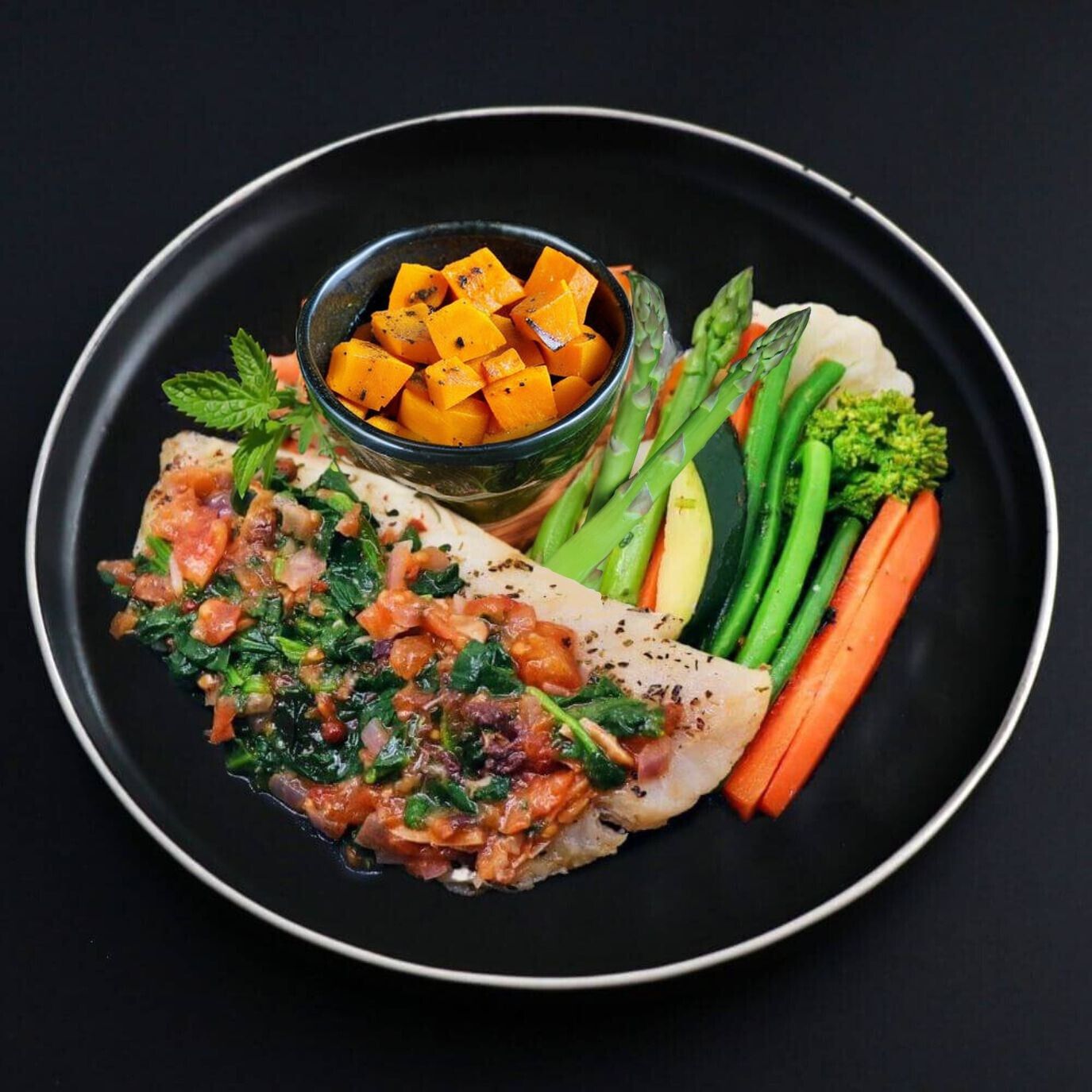 Roasted butternut squash is served on the side of a tender Cod fillet covered with Spanish spinach-tomato sauce and served with a side of assorted steamed veggies.