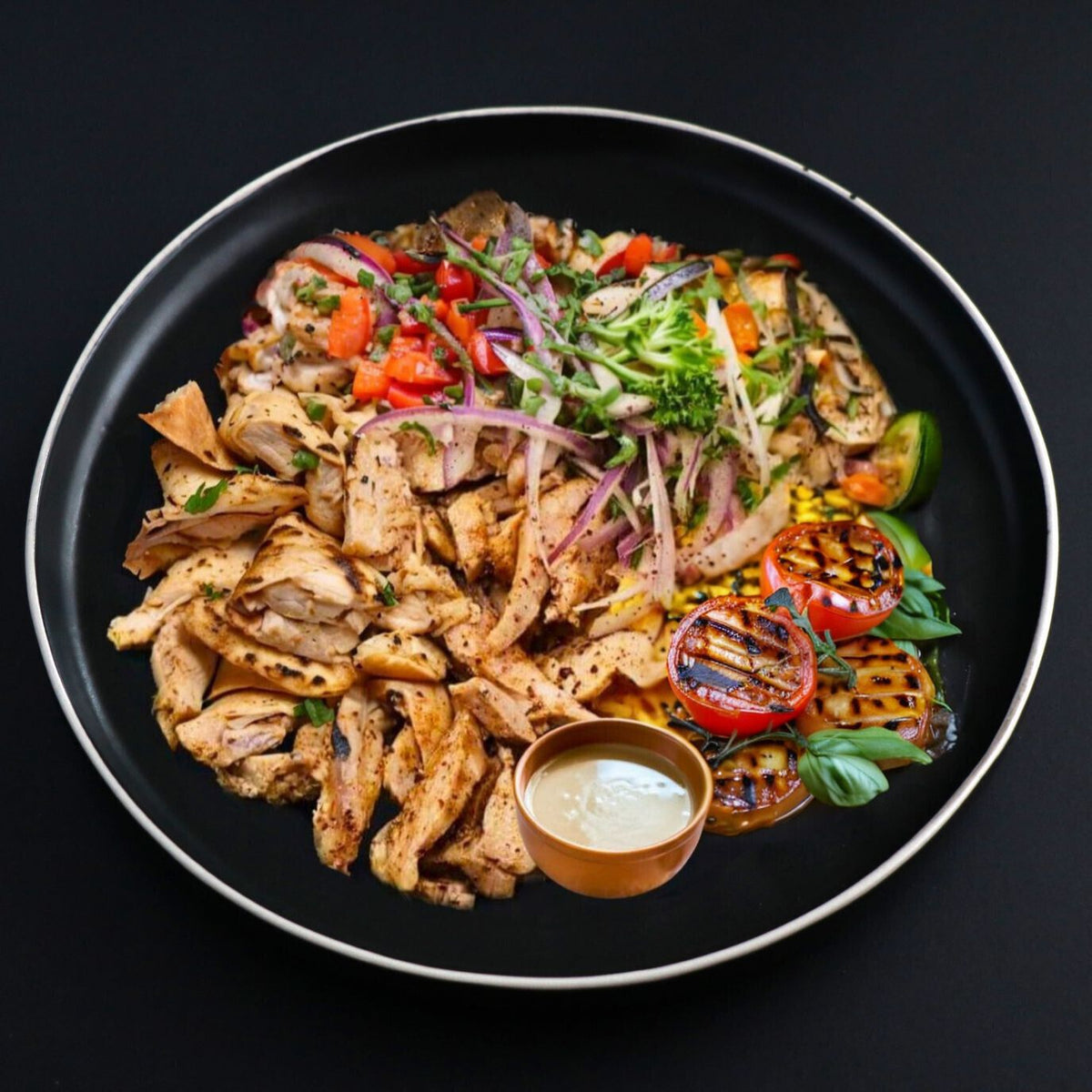 Paleo turkey shawarma bowl sided with grilled tomatoes, herbs and steamed veggies, complemented with homemade tahini.