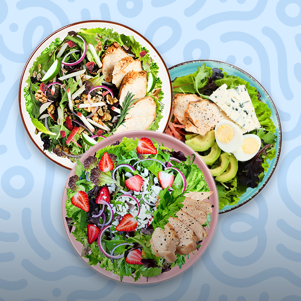 Salad variety featuring a harvest chicken salad with apples, a healthy Cobb salad with avocado and egg, and a strawberry feta chicken salad on a blue background.