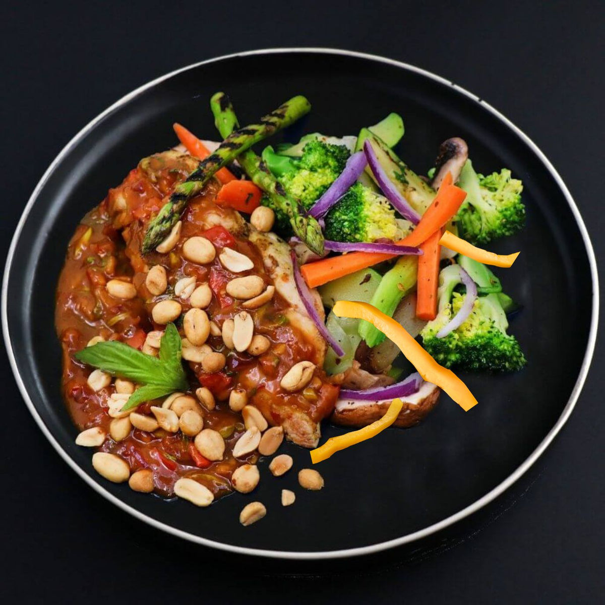 A plate of Keto Thai Chicken Curry with roasted peanuts, accompanied by steamed broccoli, carrot sticks, and assorted veggie slices.
