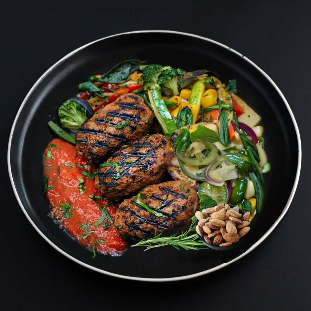 Juicy Keto beef kafta kebabs with a side of grilled assorted veggies are presented on a black place with a side of roasted almonds\.