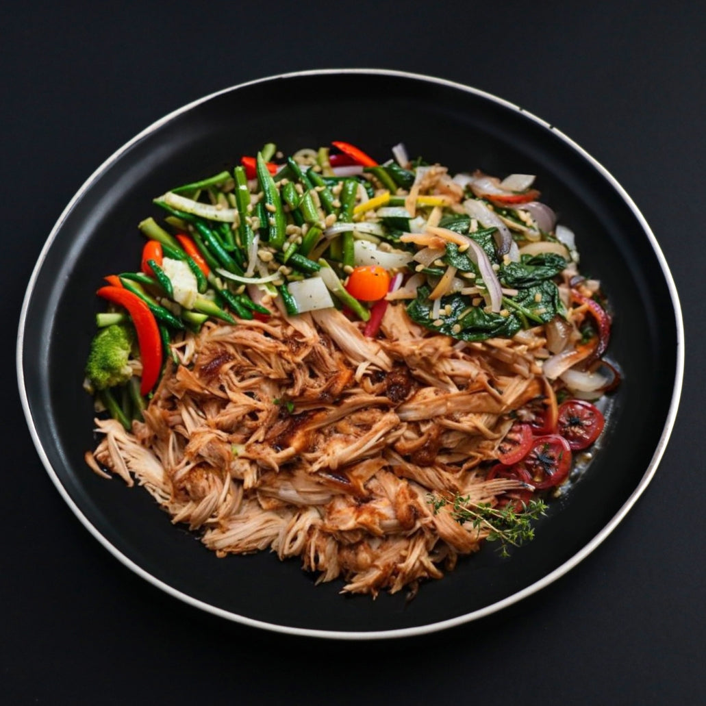 Plate of a balanced option of juicy pulled barbeque chicken thighs served with side assorted vegetables